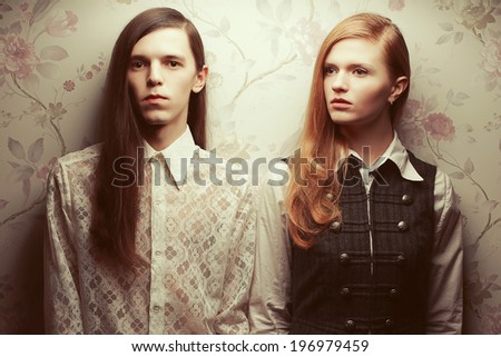 Gothic hipsters concept. Portrait of beautiful long haired people looking like dolls in vintage style: handsome guy with brown hair and gorgeous red-haired girl posing together. Studio shot