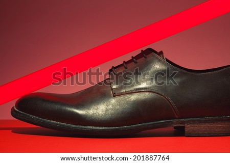 Brown leather men\'s shoes with red neon light lamp over pink and red background. Vogue style. Art fashion studio shot