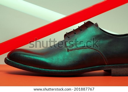 Brown leather men\'s shoes with red and white neon light lamps over gray and red background. Vogue style. Art fashion studio shot