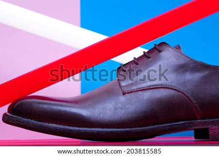 Stylish and arty hipster footwear fashion concept in disco style. Trendy leather men\'s shoes with red and white neon light lamps over pink, blue, purple background. Close up. Studio shot