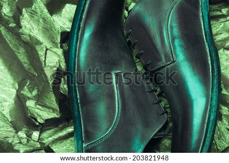 Stylish footwear fashion concept. Trendy brown leather men\'s shoes over olive-colored metal foil background. Close up. Vintage style. Studio shot