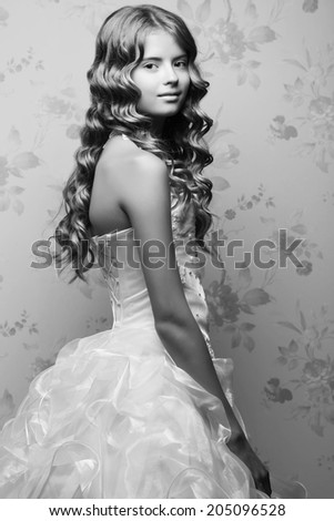 Portrait of little princess in white vapory classic dress with pearls posing over vintage background. Girl with perfect glossy long hair. Retro & Vogue style. Black and white (monochrome) studio shot