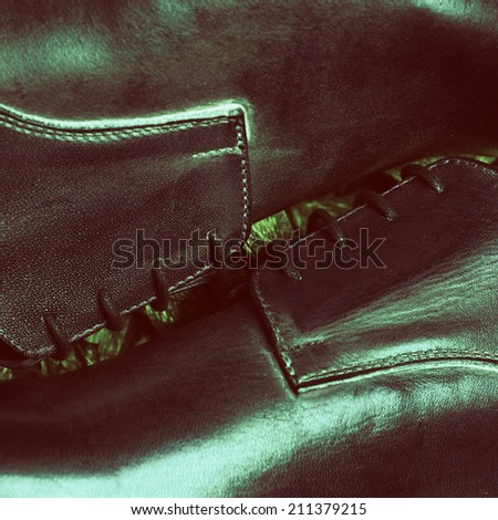Stylish footwear fashion concept. Trendy brown leather men\'s shoes over olive-colored metal foil background. Close up. Vintage style. Studio shot