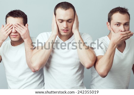 Closeup portrait of three young men in white t-shirts imitating see no evil, hear no evil, speak no evil concept, isolated on gray background. Human emotions, expressions & communication. Studio shot