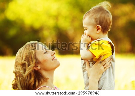Happy family, friends forever concept. Smiling mother and little son playing together in a park. Mum holding baby. Sunny windy summer day. Close up. Copy-space. Outdoor shot