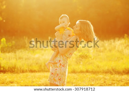 Happy family, friends forever concept. Profile portrait of mother and little son playing together in park. Mom holding baby. Sunny summer day. Vintage country style. Copy-space. Outdoor shot
