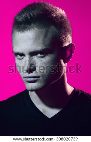 A la Andy Warhol pop-art style concept. Portrait of brutal young man with short hair wearing black t-shirt and posing over pink background. Hipster style. Close up. Studio shot