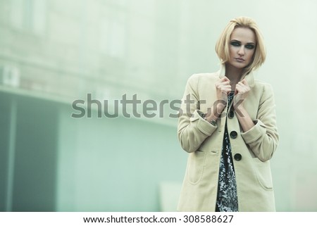 After party concept. Emotive portrait of beautiful blonde with trendy haircut in beige coat. Perfect make-up. Smoky eyes. Haute couture style. Foggy weather. Copy-space. Outdoor shot