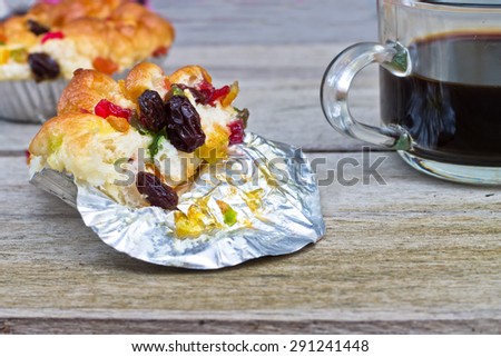Close up delicious mix dried fruit bread half  on foil cup and black coffee on old wood table