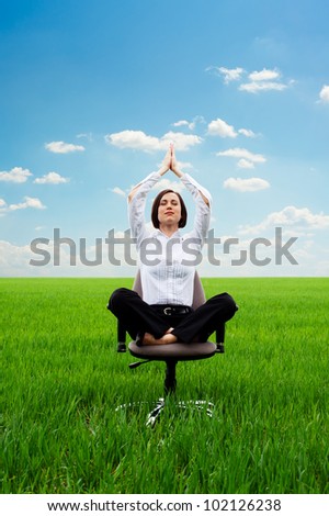 bright picture of young businesswoman practicing yoga on the meadow