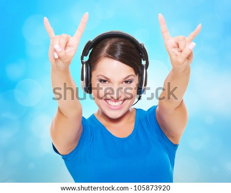 cheerful young woman in headphones giving the rock and roll sign