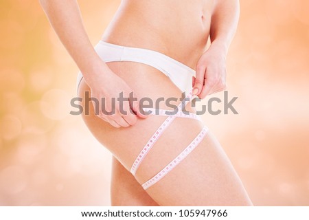 healthy slim woman measuring her hip against white background