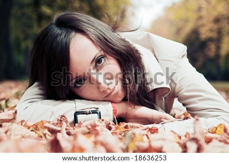 smiley woman lying on the leaves in autumn