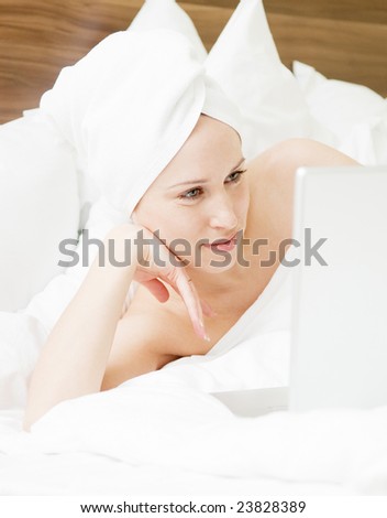 beautiful young woman lying in the bed with laptop
