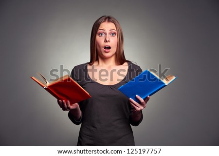 portrait of amazed woman with books over grey background