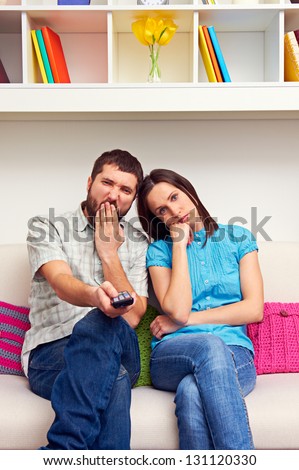 bored couple sitting on the sofa and watching TV