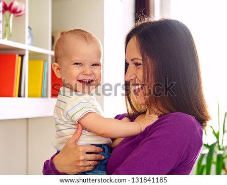 smiley woman looking at laughing kid at home