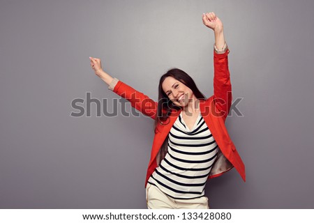 happy woman celebrating and dancing of joy winning. studio shot over dark background