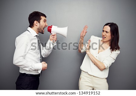 angry boss screaming in megaphone at the woman. studio shot over dark background