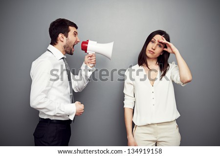 businessman screaming at the fatigued woman. studio shot over dark background