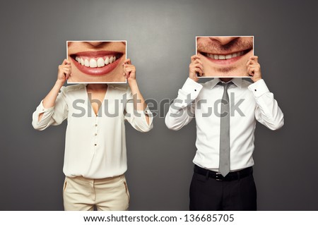 woman and man holding pictures with big smile. concept photo over dark background