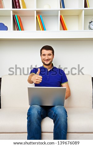 smiley man working with laptop and showing thumbs up