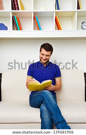 smiley man reading interesting book at home