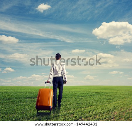back view of businessman with bag walking through the green field