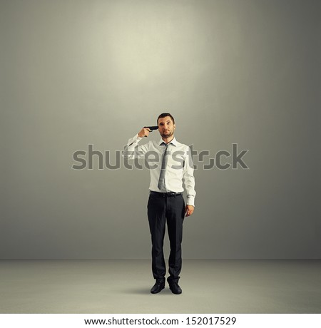 full length shot of quiet businessman with gun in dark room