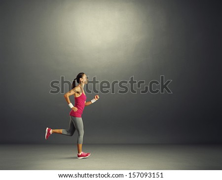 young beautiful sportswoman running in the dark room
