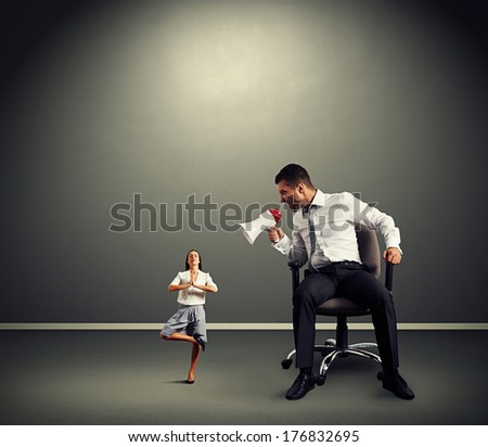 angry businessman shouting at small yoga businesswoman at dark empty room