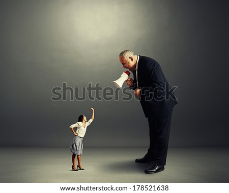 angry businessman screaming at small angry businesswoman over dark background