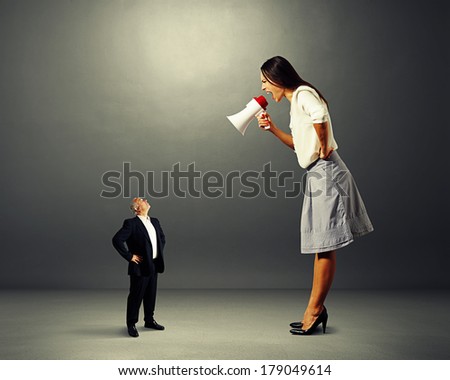 emotional woman screaming at small senior man over dark background