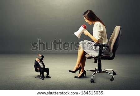angry young woman and small frightened man over dark background