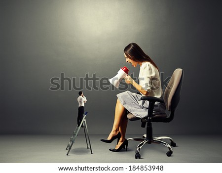 aggressive woman screaming at small man on the stepladder over dark background