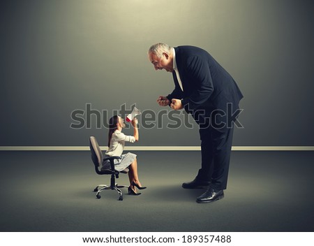 dissatisfied small woman screaming at big angry man over dark background