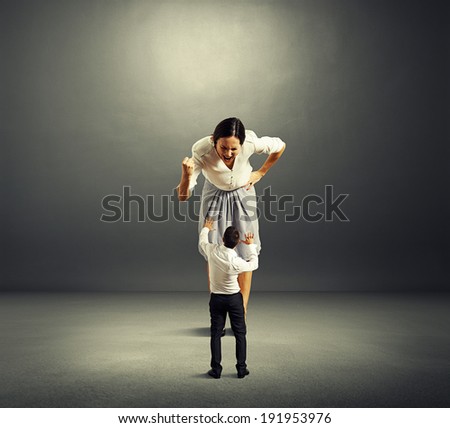 scared small man and screaming angry woman over dark background