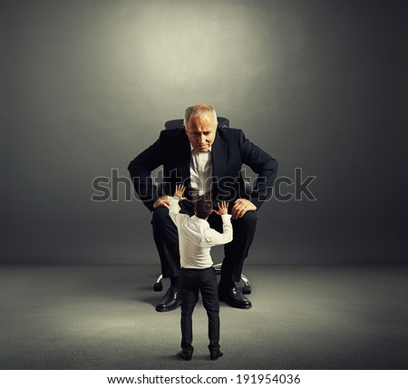 aged man looking at scared man over dark background