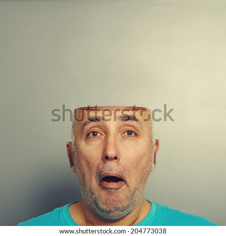concept photo of amazed senior man with open head over grey background