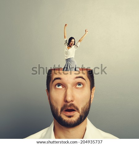 amazed young businessman with open head. young excited businesswoman dancing and raising hands up in the man\'s head. photo over grey background