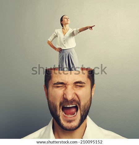 stressed screaming businessman with open head. young smiley businesswoman standing into the head and showing the direction. photo over grey background