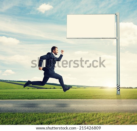 successful businessman running on the road against empty billboard and green field