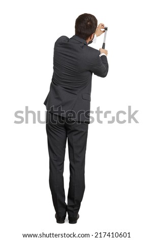 rear view of businessman hitting nail in the wall. isolated on white background