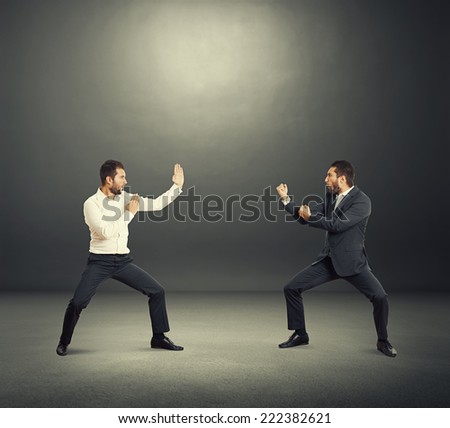 battle between two young businessmen in the dark studio