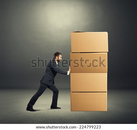smiley businessman moving cardboard boxes. photo in the dark room