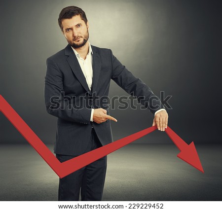 sad broker holding and pointing at falling down graph. photo over dark background