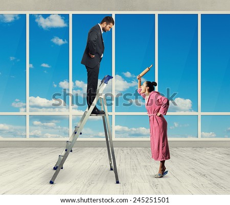dissatisfied man standing on stepladder and looking down at screaming woman with rolling pin. photo in room with big windows