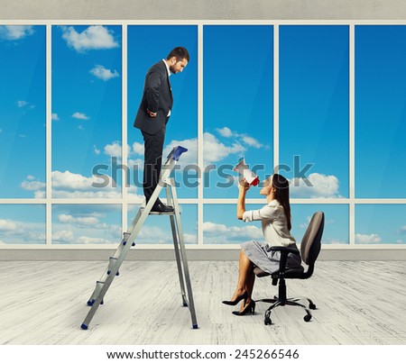 emotional businesswoman with megaphone sitting on chair and screaming at displeased businessman on stepladder. photo in empty room with big windows