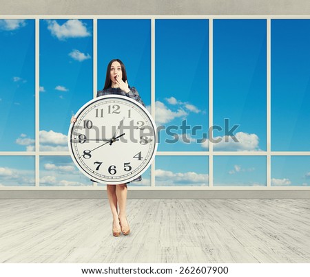 amazed woman with big white clock in empty room