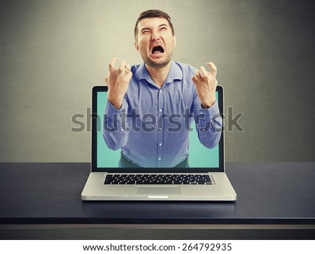 emotional screaming man got out of the laptop against dark background
